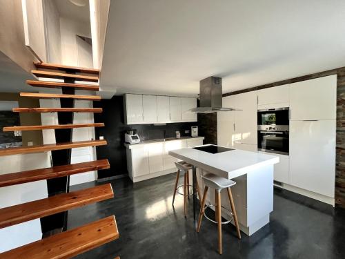 une cuisine avec des armoires blanches et une table avec des tabourets dans l'établissement Maison avec piscine, à Carpentras