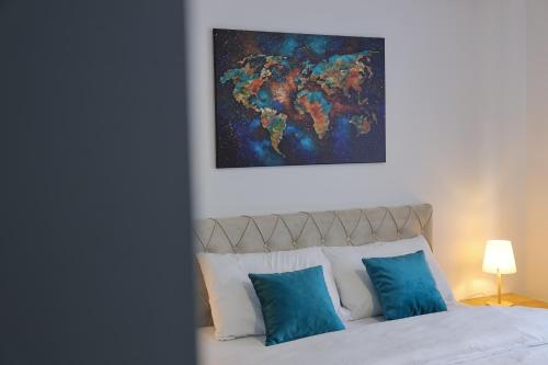 a bed with blue pillows and a painting above it at Apartmani Lepojevic in Prokuplje