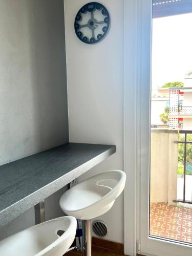two white toilets sitting next to a counter with a clock at Le maree in Grado