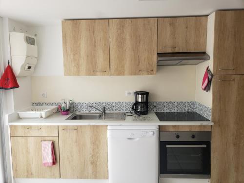 une cuisine avec des armoires en bois et un évier dans l'établissement Appartement T3 3 étoiles à 4 km de la plage, à Tarnos