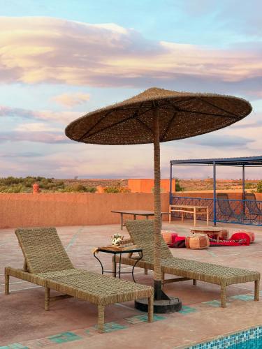 eine Terrasse mit zwei Stühlen und einem Sonnenschirm in der Unterkunft Atlas Agafay Horizon Marrakech Auberge & Luxury Suites in Aquine-Mazouz