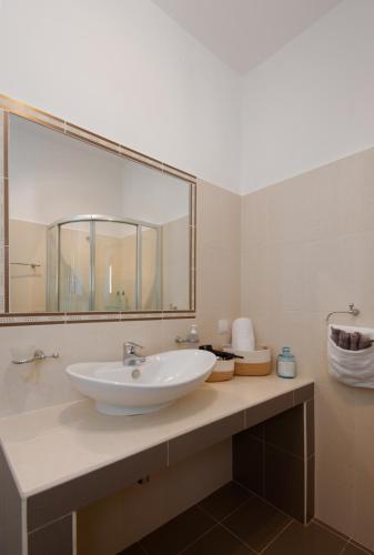 a bathroom with a sink and a large mirror at Aggeliki's House in Kamarai