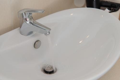 a white bathroom sink with a faucet at Aggeliki's House in Kamarai