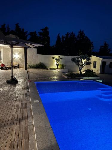 a blue swimming pool in front of a house at Villa in Kelibia