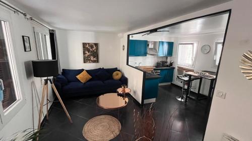 un salon avec un canapé bleu et une cuisine dans l'établissement Charmante maison de ville, à Saint-Laurent-du-Var