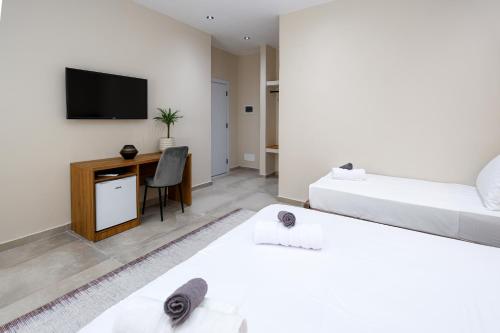 a bedroom with two beds and a desk with a television at Vila Erti Berat in Berat