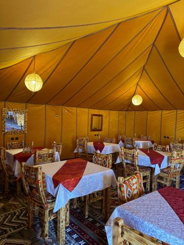 a tent with tables and chairs in a room at Desert luxury tents in Merzouga