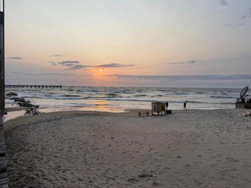 a sunset on a beach with people walking in the ocean at Aerodromas! Kunigiškiai in Palanga