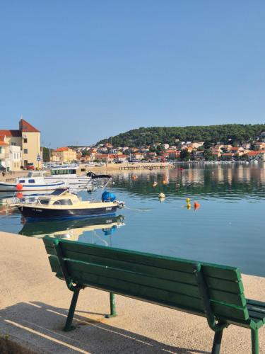 a bench next to a marina with boats in the water at Apartments Valentina Tisno in Tisno
