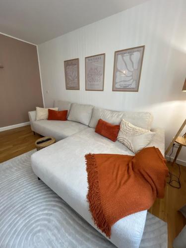 a living room with a white couch with orange pillows at Gemütliches Apartment I Mitten in der Stadt Aschaffenburg I 5 Min HBF I Gegenüber City Galerie in Aschaffenburg