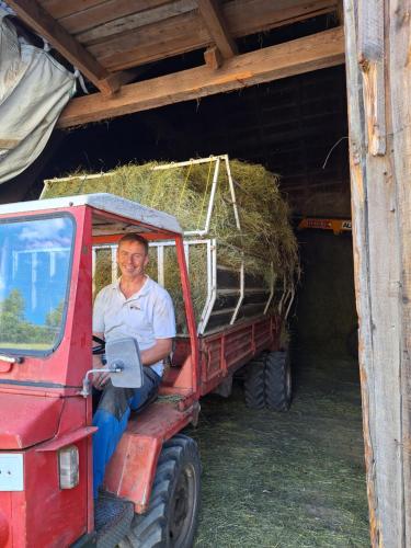 a man sitting in the back of a tractor with hay at Boabauer in Tamsweg