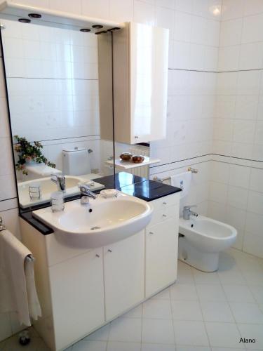 a white bathroom with a sink and a toilet at Mon Refuge Villa Deluxe in Correzzola