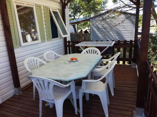 - une table et des chaises sur la terrasse couverte arrière d'une maison dans l'établissement Mobil-Home Clermont-Auvergne, à Sigean
