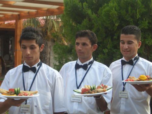 three men wearing bow ties holding plates of food at Perdikia Beach in Oludeniz