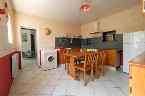 une cuisine avec une table et des chaises ainsi qu'un lave-linge dans l'établissement Soleil Levant, petite maison de caractère à prix bas, à Saint-Georges-de-Pointindoux
