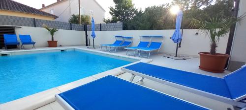 a large swimming pool with blue chairs and umbrellas at VILLA BIANCA - Holiday home with Private pool in Privlaka