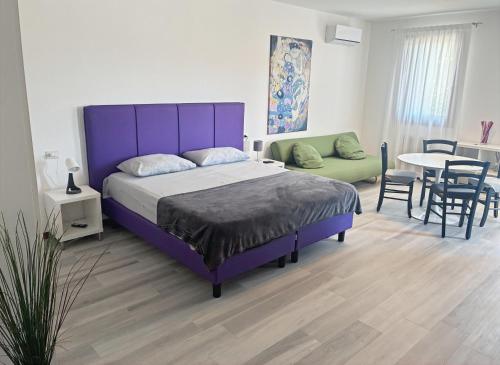 a bedroom with a purple bed and a table and chairs at Agriturismo Al Preve in Ponzano Veneto