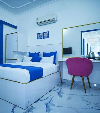 a bedroom with a bed and a purple chair at The Host By Amaris in Amritsar
