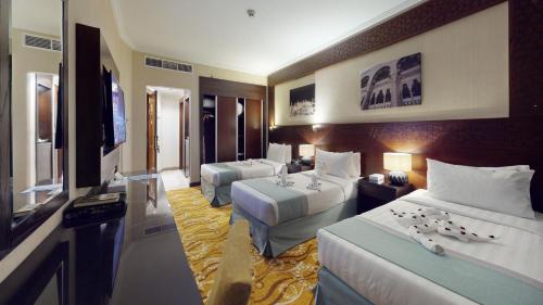 a hotel room with two beds and a flat screen tv at جراند الشهباء Grand Alshahba Hotel in Al Madinah