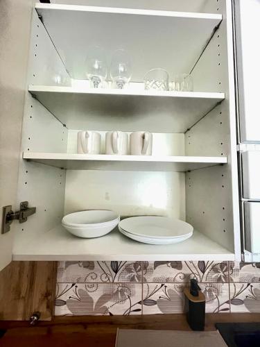 a white shelf with plates and glasses on it at Apartman Cañas Zelená Víla in Rimavská Sobota