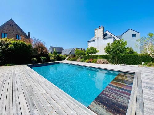 - une piscine dans une cour avec une terrasse en bois dans l'établissement Villa le 25 - Piscine et Sauna au bourg de Carantec, à Carantec