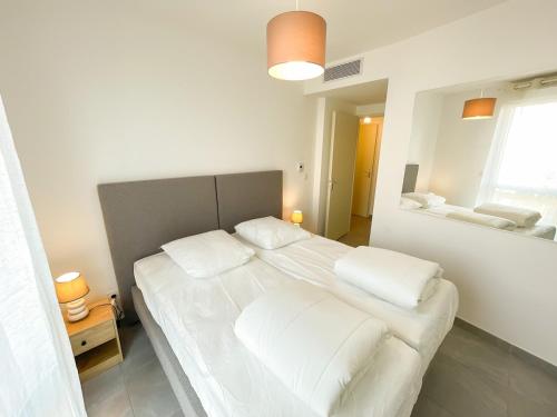 une chambre avec un grand lit avec des draps et des oreillers blancs dans l'établissement Joli T3 au coeur de Sanary avec garage, à Sanary-sur-Mer
