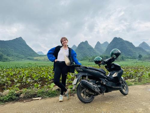 a woman is standing next to a motorcycle at PIA homestay - Tours & Motorbike rentals - Cao Bằng in Cao Bằng