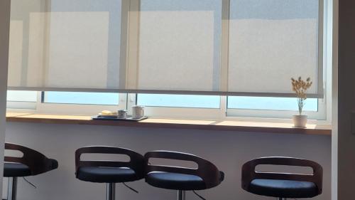 un bar avec des tabourets noirs devant une fenêtre dans l'établissement Oceandream vue sur l'ocean 6 personnes Nouveau !, à La Parée Preneau