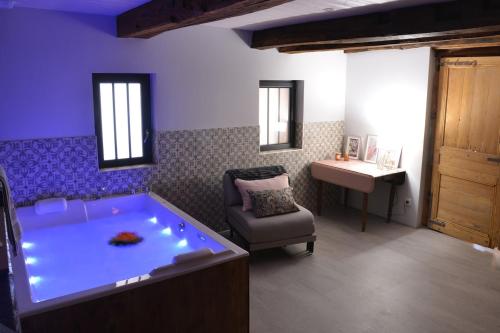 a large tub in a room with a chair and a sink at Gite L étable du Bien Etre in Léré