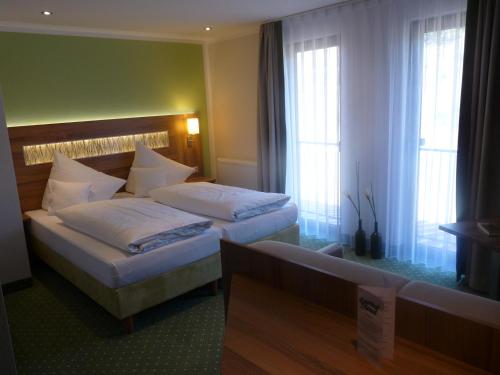 ein Hotelzimmer mit 2 Betten und 2 Fenstern in der Unterkunft Hotel- Landgasthof Baumhof-Tenne in Marktheidenfeld