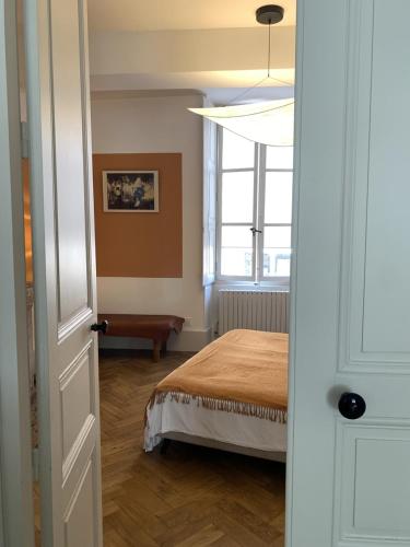 une chambre avec un lit et une fenêtre dans l'établissement Maison Thaïs, deux pièces de charme, à Autun