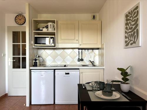 une cuisine avec des placards blancs et une table noire dans l'établissement Peaceful apartment with sea and hill view, air-conditioned, à Roquebrune-sur Argens