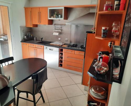 une cuisine avec des armoires en bois et une table avec des chaises dans l'établissement Appartement 2 CH résidence calme et arborée , proximité plages et commerces, à Toulon