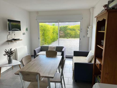 a living room with a table and a couch at L'Echappée Verte - Guînes, maison 2 chambres à 25min du Site des 2 Caps in Guînes