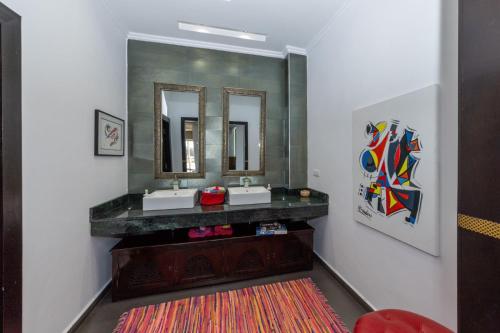 a bathroom with two sinks and two mirrors at Asmae House in Skhirat