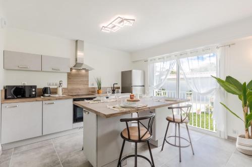 une cuisine avec des placards blancs et un îlot avec des tabourets de bar dans l'établissement Le Lonsois - T3 lumineux avec extérieur, à Pau