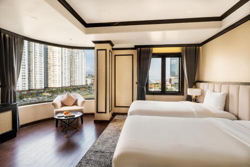 Habitación de hotel con 2 camas, silla y ventana en FTE Ha Long Hotel, en Ha Long