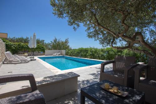 a swimming pool with chairs and a table next to it at Apartments Niana with heated swimingpool in Okrug Donji