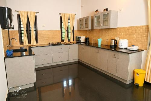 a large kitchen with white cabinets and counters at The Greeen Pod- Adamya Homestay in Aldūr