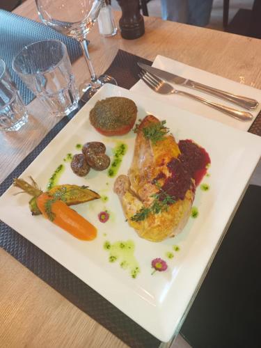 a white plate with a chicken and vegetables on a table at Hôtel le Christiania in Arêches