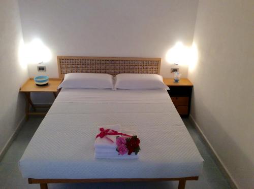a bedroom with a white bed with a bouquet of flowers on it at Dimora Tipica Vista Mare in Marettimo