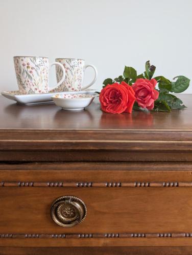 a wooden dresser with two cups and roses on it at Al tempo ritrovato Country house in Pianfei