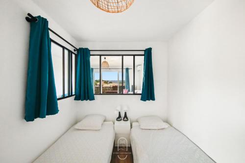- 2 lits dans une chambre dotée de rideaux bleus dans l'établissement Le Phare Giens CLIM/WIFI/PARKING, à Hyères