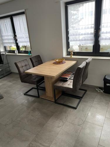 a wooden table and chairs in a room with windows at Schönes Appartement in der Nähe vom Schloss Herten in Gelsenkirchen
