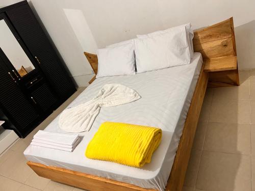 a bed with a yellow towel on top of it at AnnexSarova Homestay in Migombani