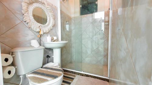 a bathroom with a toilet and a shower with a mirror at Casa Mar e Mar in Cabo Frio