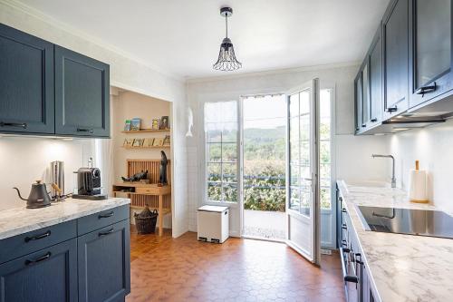 une cuisine avec des placards bleus et une grande fenêtre dans l'établissement 'Maison Bellevue', à Corancy