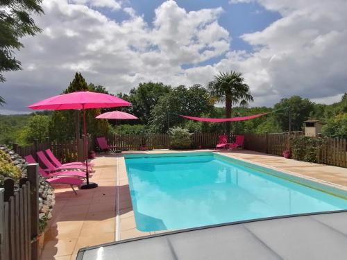 une piscine avec deux parasols et deux chaises et un parasol rose dans l'établissement Les gîtes du hameau d'Auriac, à Calès