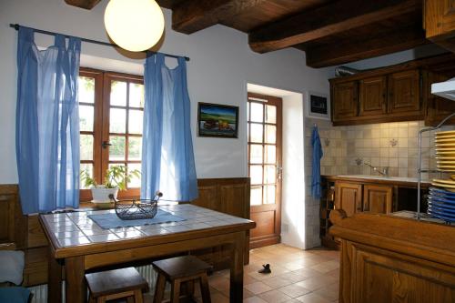 une cuisine avec une table et des rideaux bleus dans l'établissement Les gîtes du hameau d'Auriac, à Calès