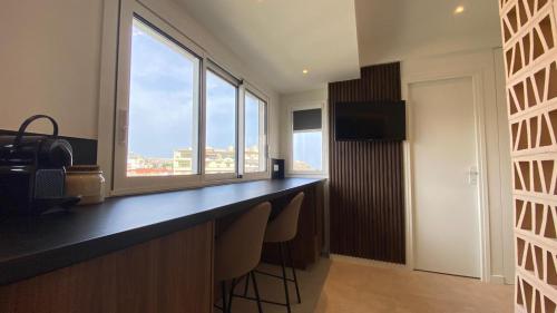 - une cuisine avec un bar avec des chaises et des fenêtres dans l'établissement Cannes Croisette, à Cannes